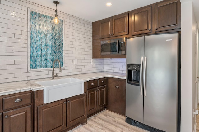 kitchen with appliances with stainless steel finishes, light hardwood / wood-style floors, tasteful backsplash, and sink