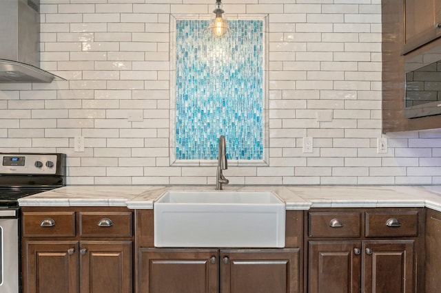 kitchen featuring pendant lighting, tasteful backsplash, stainless steel electric range oven, and sink