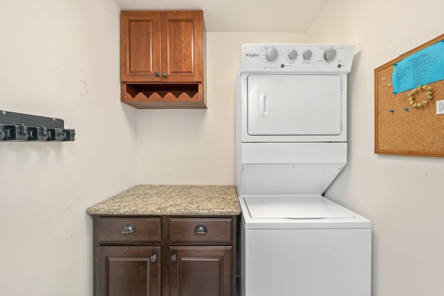 washroom featuring cabinets and stacked washer and clothes dryer