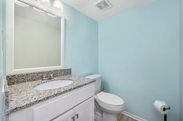 bathroom with hardwood / wood-style floors, vanity, and toilet