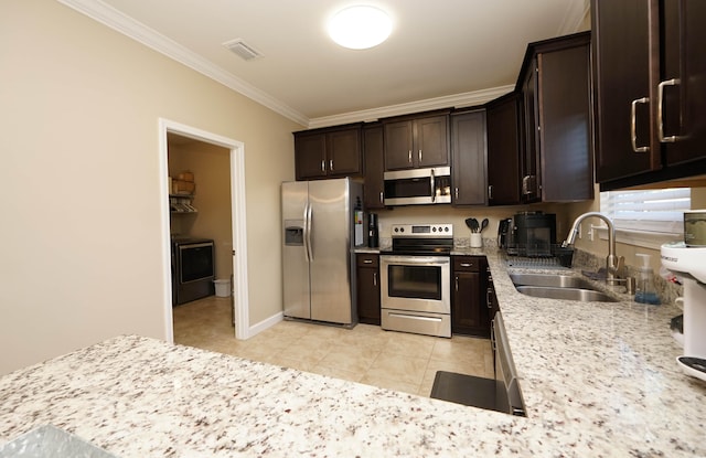 kitchen with crown molding, sink, appliances with stainless steel finishes, washer / dryer, and dark brown cabinetry