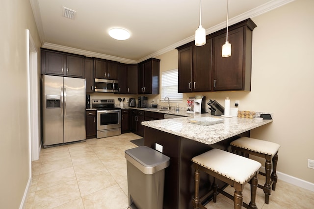 kitchen featuring dark brown cabinetry, stainless steel appliances, pendant lighting, a kitchen bar, and ornamental molding