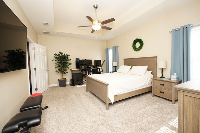 carpeted bedroom featuring ceiling fan and a raised ceiling