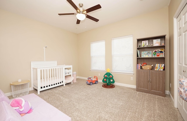 carpeted bedroom featuring ceiling fan and a crib