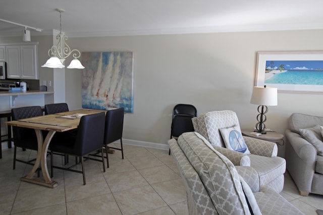 dining room with a chandelier, light tile patterned floors, track lighting, and ornamental molding