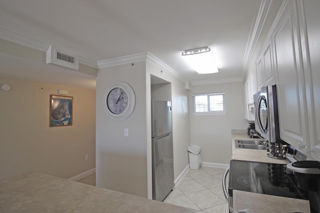 kitchen featuring white cabinets, sink, light tile patterned floors, ornamental molding, and appliances with stainless steel finishes