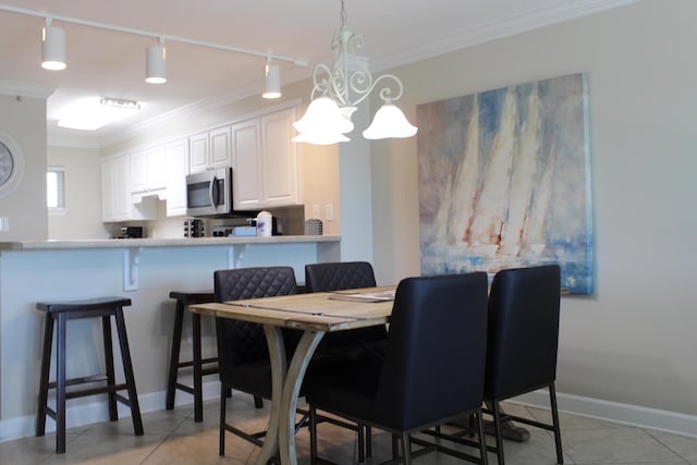 tiled dining space featuring a chandelier, track lighting, and crown molding