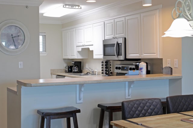 kitchen with a kitchen breakfast bar, sink, hanging light fixtures, ornamental molding, and white cabinetry