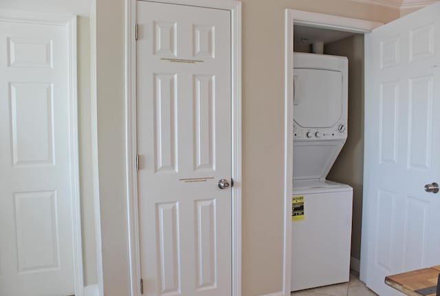 clothes washing area featuring light tile patterned flooring and stacked washer and clothes dryer