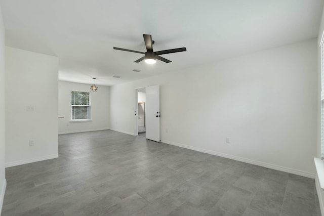 spare room featuring ceiling fan with notable chandelier