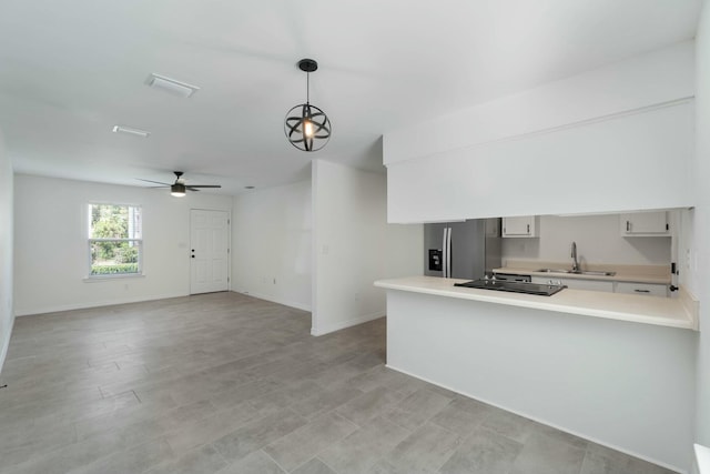 kitchen with kitchen peninsula, stainless steel fridge, ceiling fan, sink, and hanging light fixtures