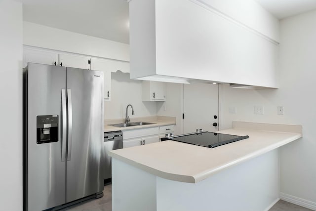 kitchen featuring premium range hood, white cabinets, sink, appliances with stainless steel finishes, and kitchen peninsula