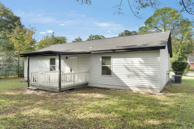 rear view of property featuring central air condition unit, a wooden deck, and a lawn