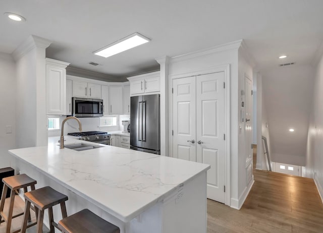 kitchen featuring high end appliances, white cabinetry, crown molding, and light hardwood / wood-style flooring