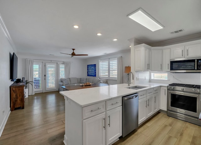 kitchen with a wealth of natural light, kitchen peninsula, sink, and appliances with stainless steel finishes