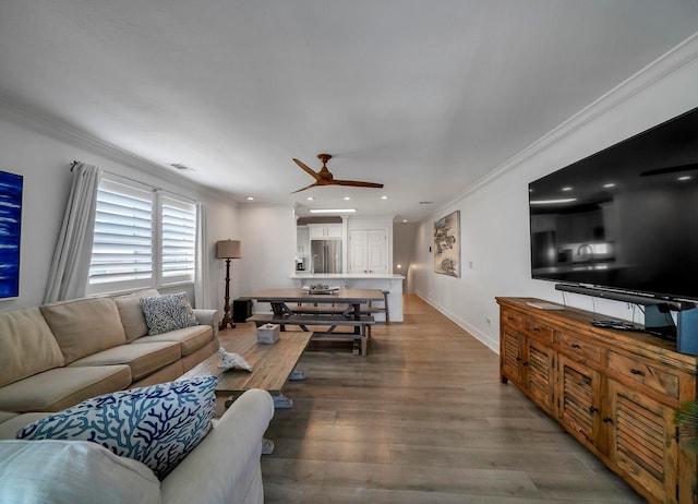 living room with hardwood / wood-style floors, ceiling fan, and crown molding