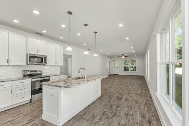 kitchen with white cabinets, appliances with stainless steel finishes, ceiling fan, and hardwood / wood-style floors