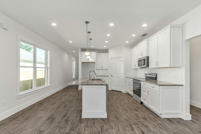 kitchen featuring pendant lighting, a kitchen island with sink, dark wood-type flooring, white cabinetry, and stainless steel appliances