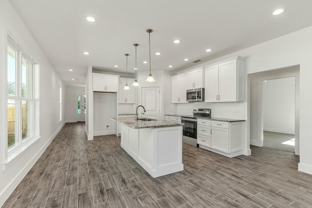 kitchen with sink, stainless steel appliances, white cabinetry, and an island with sink