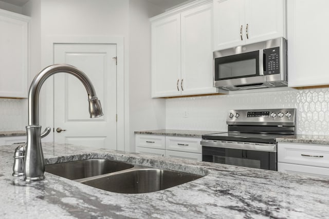 kitchen with white cabinets, light stone counters, sink, and appliances with stainless steel finishes