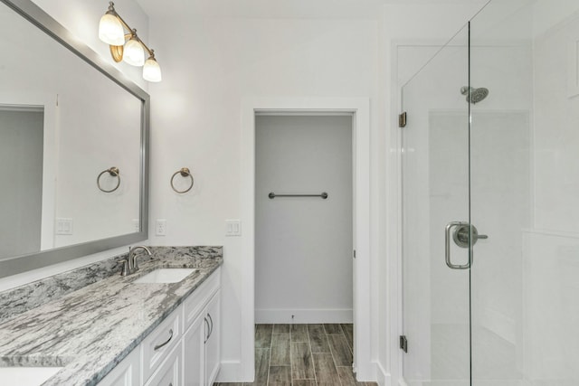 bathroom with hardwood / wood-style floors, vanity, and a shower with door