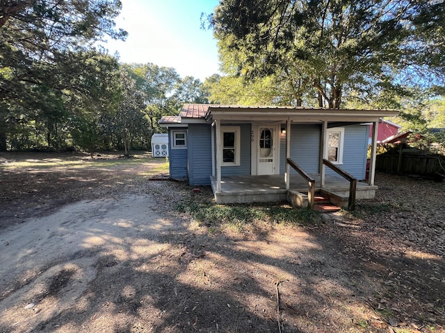 view of front of property featuring covered porch and a storage shed