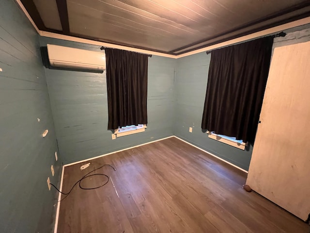 empty room featuring a wall mounted air conditioner, hardwood / wood-style flooring, and wooden ceiling