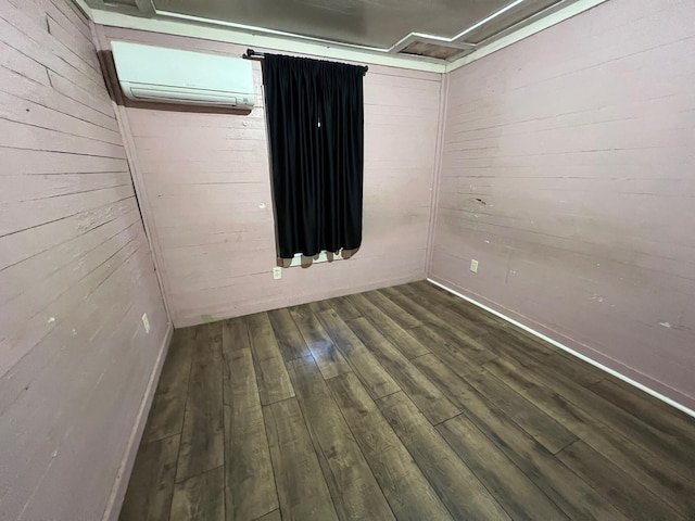 spare room with a wall mounted air conditioner, wood-type flooring, and wooden walls