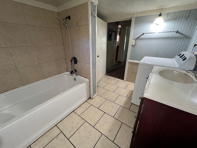 bathroom with vanity, wood walls, tile patterned flooring, tiled shower / bath combo, and independent washer and dryer