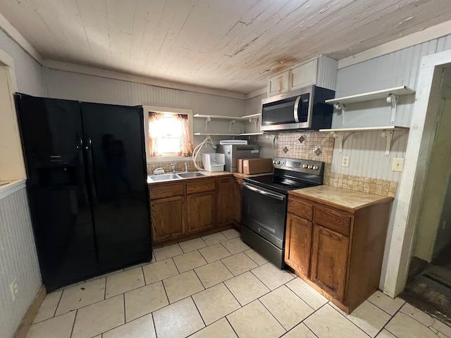 kitchen featuring range with electric cooktop, backsplash, black fridge with ice dispenser, sink, and wood walls