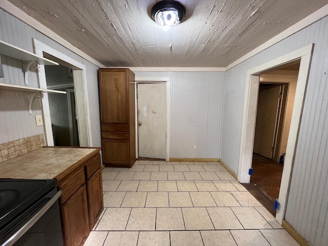 kitchen with light tile patterned floors, tile counters, and wooden walls