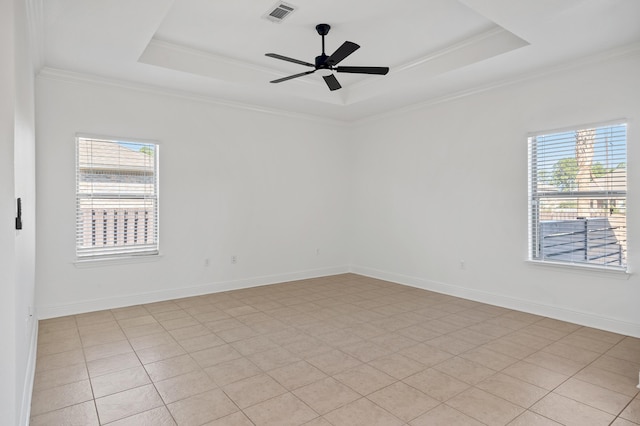 empty room featuring a raised ceiling, a wealth of natural light, crown molding, and ceiling fan