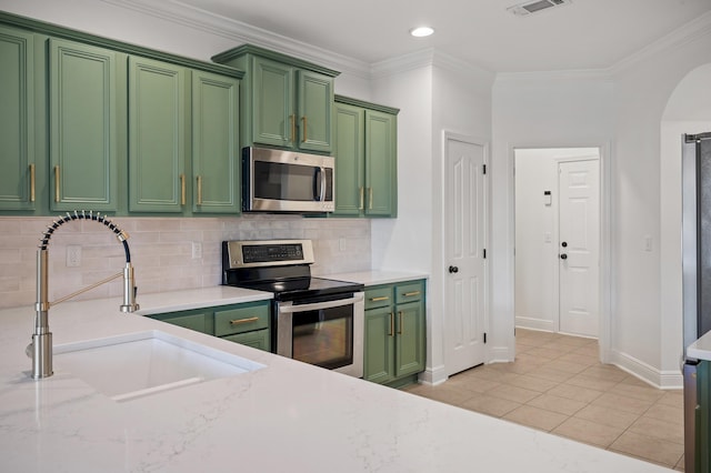 kitchen featuring crown molding, sink, green cabinetry, light tile patterned floors, and stainless steel appliances