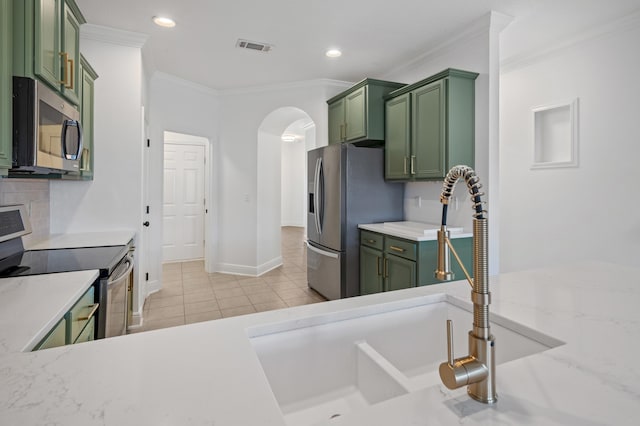 kitchen featuring appliances with stainless steel finishes, ornamental molding, and green cabinets