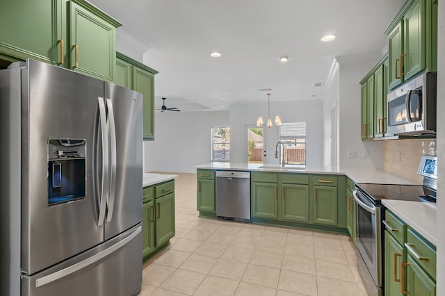 kitchen featuring ornamental molding, ceiling fan with notable chandelier, stainless steel appliances, and green cabinets