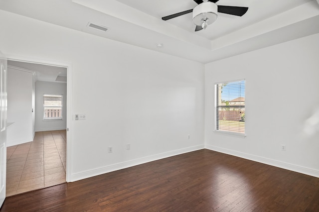 unfurnished room featuring dark hardwood / wood-style flooring, a tray ceiling, and ceiling fan