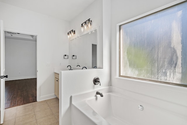 bathroom with tile patterned flooring, a bath, and vanity