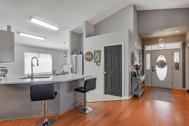 9761 Leeward Way, Navarre, FL 32566 - kitchen featuring stainless steel fridge, a sink, light countertops, light wood-type flooring, and a breakfast bar area