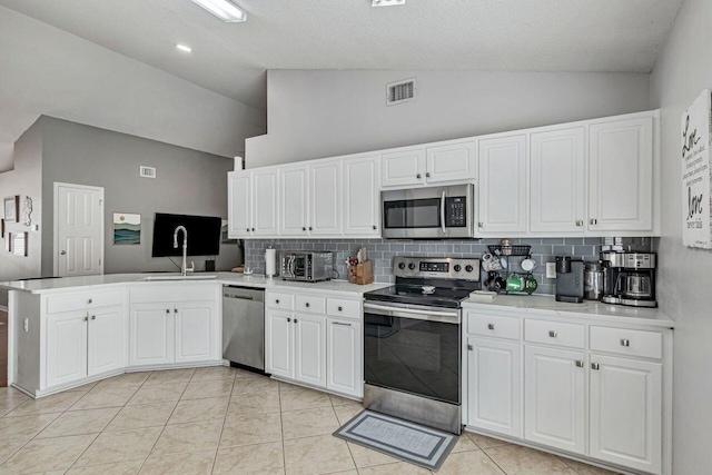 kitchen featuring sink, kitchen peninsula, light tile patterned flooring, white cabinetry, and stainless steel appliances