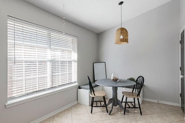 dining area featuring light tile patterned floors, a healthy amount of sunlight, and lofted ceiling