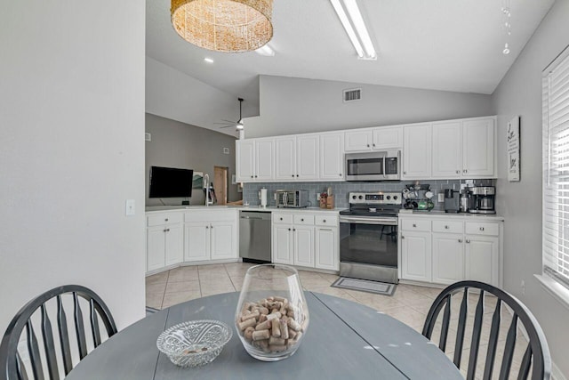 kitchen with ceiling fan, stainless steel appliances, tasteful backsplash, white cabinets, and light tile patterned flooring