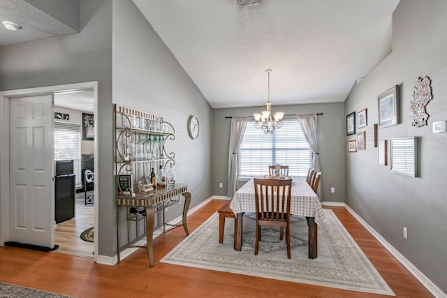 9761 Leeward Way, Navarre, FL 32566 - dining space featuring a chandelier, wood finished floors, a textured ceiling, baseboards, and lofted ceiling