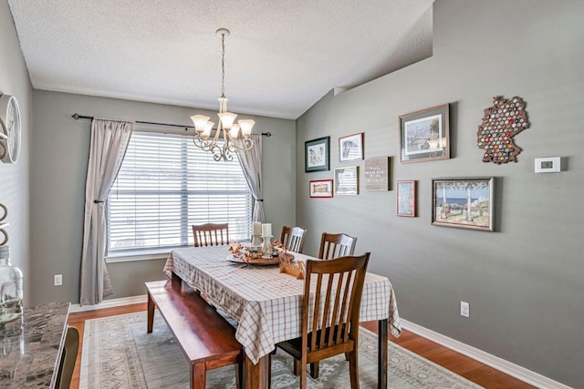 dining area featuring hardwood / wood-style floors, a textured ceiling, and a notable chandelier