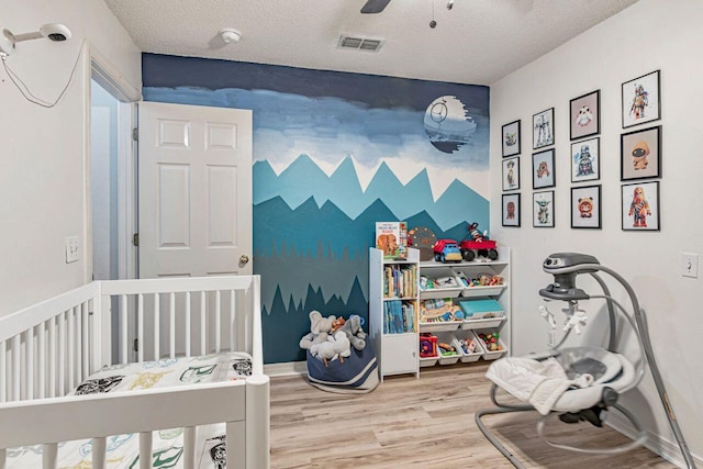 9761 Leeward Way, Navarre, FL 32566 - bedroom featuring wood finished floors, a textured ceiling, ceiling fan, and a crib