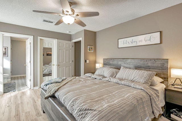 9761 Leeward Way, Navarre, FL 32566 - bedroom featuring light wood-type flooring, a textured ceiling, ceiling fan, and ensuite bathroom