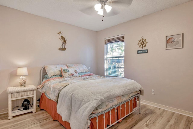 bedroom with a textured ceiling, light wood-type flooring, and ceiling fan