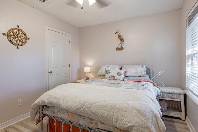 bedroom featuring ceiling fan, wood-type flooring, and a textured ceiling