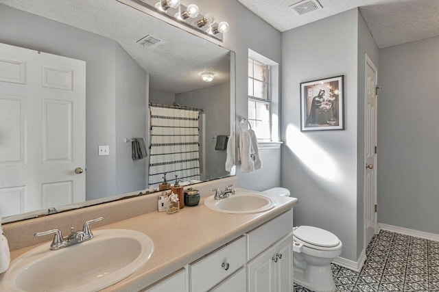 9761 Leeward Way, Navarre, FL 32566 - bathroom featuring toilet, a textured ceiling, double vanity, and baseboards