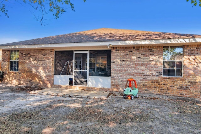 9761 Leeward Way, Navarre, FL 32566 - rear view of house with brick siding, a sunroom, and roof with shingles