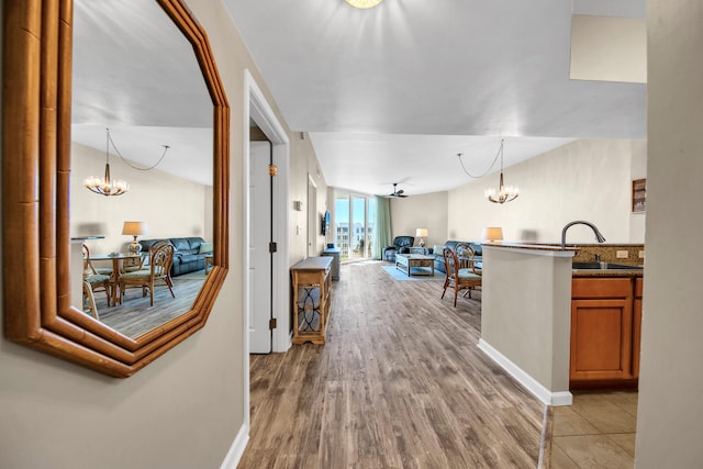 hall with light wood-type flooring, sink, and a chandelier